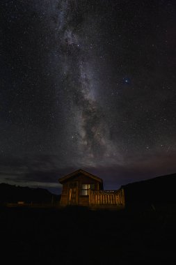 Cozy wooden cabin sits under a breathtaking night sky filled with the Milky Way galaxys brilliance. Icelandic night sky. Snaefellsnes peninsula. clipart