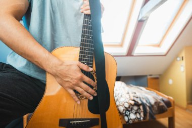 Akustik gitar çalma perspektifi, parmaklar fretboard 'a bastırıyor, doğal ahşabın sıcaklığını yakalıyor, tellerin tınısını yakalıyor. Kapalı mekan müziği.