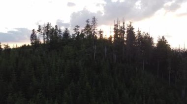 Bir dağın arkasındaki günbatımının hava manzarası manzaranın son kalıntılarını aydınlatıyor. Beskydy Dağları, Çek Cumhuriyeti.