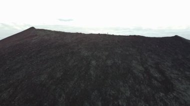Explorer soyu tükenmiş bir volkanın zirvesinde duruyor. Batı İzlanda 'daki Snaefellsnes Yarımadası' ndaki bir vadiye bakıyor. İnanılmaz bir doğa. İyileşme. 4K yatay video