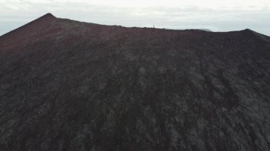 Explorer soyu tükenmiş bir volkanın zirvesinde duruyor. Batı İzlanda 'daki Snaefellsnes Yarımadası' ndaki bir vadiye bakıyor. İnanılmaz bir doğa. İyileşme. 4K yatay video