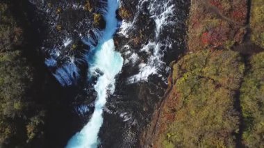 Kristal berraklığında buzul, İzlanda 'daki çarpıcı Bruarfoss şelalesinde engebeli volkanik kayaların arasından dökülür..