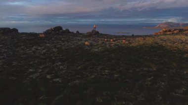 Dünyanın kıyısında, son uçurumun kıyısında İzlanda Snaefellsnes Yarımadası boyunca okyanusa dalıyor. İnsanlar korku içinde durup okyanusun derinliklerine bakarlar. Gökyüzü nefes kesen bir günbatımıyla yanarken..