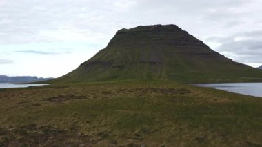 Macera ruhuna sahip bir adam, Batı İzlanda 'daki ünlü İzlanda dağı Kirkjufell' e doğru yürüyor. 4K video.