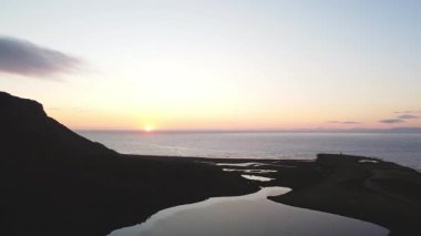 İzlanda Snaefellsnes Yarımadası 'ndaki Atlantik Okyanusu' na yakın tatlı su gölleri ve kıvrımlı bir nehrin havadan çekilmiş görüntüsü, gün batımının altın parıltısıyla yıkanmış. 4k video