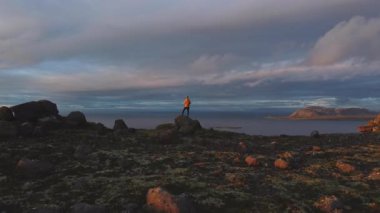 Dünyanın kıyısında, son uçurumun kıyısında İzlanda Snaefellsnes Yarımadası boyunca okyanusa dalıyor. İnsanlar korku içinde durup okyanusun derinliklerine bakarlar. Gökyüzü nefes kesen bir günbatımıyla yanarken..