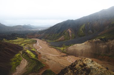 Landmannalaugar, İzlanda 'daki renkli rhyolite dağlarının ve dolambaçlı derenin manzarası. Zamanla ve ham doğal güçlerle şekillenen gerçeküstü volkanik bir manzara. Ünlü İzlanda mekanı.