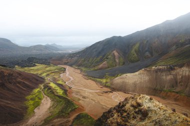 Landmannalaugar, İzlanda 'daki renkli rhyolite dağlarının ve dolambaçlı derenin manzarası. Zamanla ve ham doğal güçlerle şekillenen gerçeküstü volkanik bir manzara. Ünlü İzlanda mekanı.