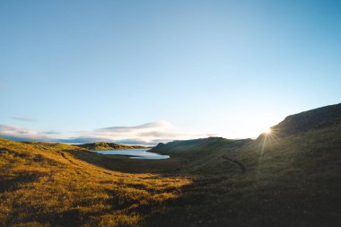 Hrunamannahreppur, İzlanda 'daki Hrunamannahreppur Dağı yakınlarındaki sakin göl ve yuvarlanan tepeler üzerinde altın saat. İzlanda kırsalında huzurlu bir günbatımı anı.
