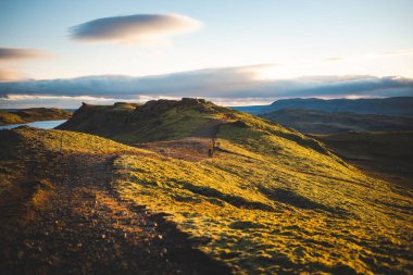 Hrunamannahreppur, İzlanda 'daki Hrunamannahreppur Dağı yakınlarındaki sakin göl ve yuvarlanan tepeler üzerinde altın saat. İzlanda kırsalında huzurlu bir günbatımı anı.