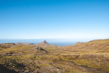 Sırt çantalı yalnız yürüyüşçü, İzlanda 'nın gerçeküstü volkanik dağlarını keşfeder. Altın yosunların karamsar kayaların altında kara lav kayalarıyla buluştuğu, el değmemiş ve destansı bir yer.