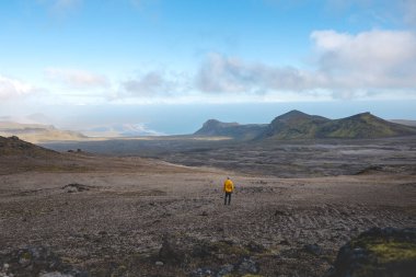 Sırt çantalı yalnız yürüyüşçü, İzlanda 'nın gerçeküstü volkanik dağlarını keşfeder. Altın yosunların karamsar kayaların altında kara lav kayalarıyla buluştuğu, el değmemiş ve destansı bir yer.