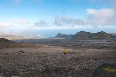 Sırt çantalı yalnız yürüyüşçü, İzlanda 'nın gerçeküstü volkanik dağlarını keşfeder. Altın yosunların karamsar kayaların altında kara lav kayalarıyla buluştuğu, el değmemiş ve destansı bir yer.
