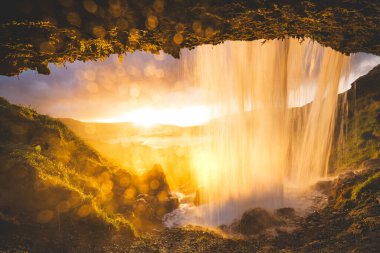 İzlanda 'nın batısındaki Snaefellsnes Yarımadası' nda Selvallafoss şelalesi. Arkasından yakalanan soğuk, berrak su çağlayanı gibi büyülü bir günbatımının önünde..