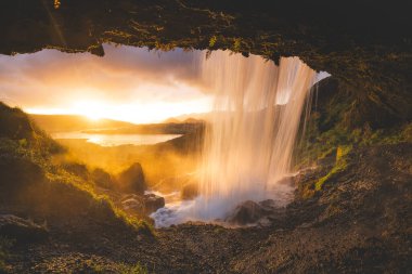İzlanda 'nın batısındaki Snaefellsnes Yarımadası' nda Selvallafoss şelalesi. Arkasından yakalanan soğuk, berrak su çağlayanı gibi büyülü bir günbatımının önünde..