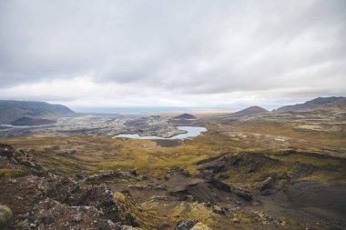 İzlanda 'da Snaefellsnes yarımadasındaki volkanik alanlar, göller ve kraterler üzerindeki hava manzarası karamsar bir gökyüzü altında ham doğal dokular ve jeolojik zıtlıklar sergiliyor..