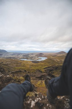 İzlanda 'nın Snaefellsnes yarımadasındaki Boynuz Dağı' nın sonunda tek başına yürüyen yürüyüşçü batan güneşten gelen altın ışık aşağıdaki engebeli volkanik araziyi aydınlatıyor. Kenarda dur..