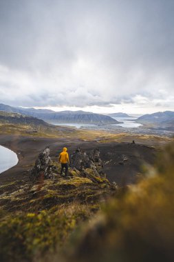 İzlanda 'nın Snaefellsnes yarımadasındaki Boynuz Dağı' nın sonunda tek başına yürüyen yürüyüşçü batan güneşten gelen altın ışık aşağıdaki engebeli volkanik araziyi aydınlatıyor. Kenarda dur..