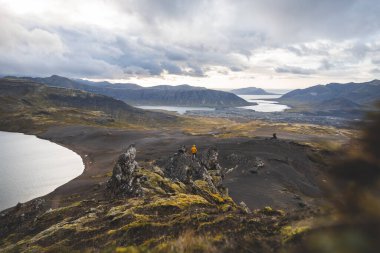 İzlanda 'nın Snaefellsnes yarımadasındaki Boynuz Dağı' nın sonunda tek başına yürüyen yürüyüşçü batan güneşten gelen altın ışık aşağıdaki engebeli volkanik araziyi aydınlatıyor. Kenarda dur..