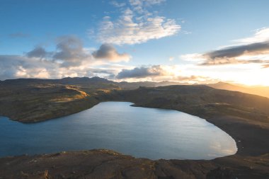 Altın güneş ışığı, İzlanda 'daki Snaefellsnes Yarımadası' ndaki Boynuz adlı dağın ufukta parlıyor. Gökyüzüne ve aşağıdaki volkanik topraklara çarpıcı bir ışık saçıyor..