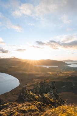 İzlanda 'nın Snaefellsnes yarımadasındaki Boynuz Dağı' nın sonunda tek başına yürüyen yürüyüşçü batan güneşten gelen altın ışık aşağıdaki engebeli volkanik araziyi aydınlatıyor. Kenarda dur..