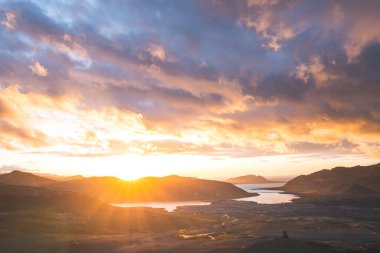 Altın güneş ışığı, İzlanda 'daki Snaefellsnes Yarımadası' ndaki Boynuz adlı dağın ufukta parlıyor. Gökyüzüne ve aşağıdaki volkanik topraklara çarpıcı bir ışık saçıyor..