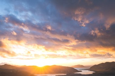 Altın güneş ışığı, İzlanda 'daki Snaefellsnes Yarımadası' ndaki Boynuz adlı dağın ufukta parlıyor. Gökyüzüne ve aşağıdaki volkanik topraklara çarpıcı bir ışık saçıyor..