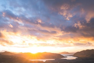 Altın güneş ışığı, İzlanda 'daki Snaefellsnes Yarımadası' ndaki Boynuz adlı dağın ufukta parlıyor. Gökyüzüne ve aşağıdaki volkanik topraklara çarpıcı bir ışık saçıyor..