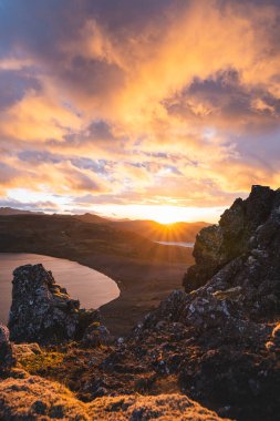 Altın güneş ışığı, İzlanda 'daki Snaefellsnes Yarımadası' ndaki Boynuz adlı dağın ufukta parlıyor. Gökyüzüne ve aşağıdaki volkanik topraklara çarpıcı bir ışık saçıyor..