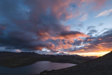 İzlanda 'daki Snaefellsnes yarımadasındaki bir dağ gölünün üzerinde altın güneş ışığı gökyüzüne ve aşağıdaki volkanik araziye çarpıcı bir ışık saçıyor. Masal günbatımı.