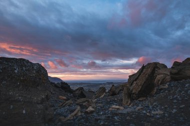 İzlanda 'daki Snaefellsnes yarımadasındaki volkanik kayaların üzerinde sürüklenen renkli bulutlar günün son ışığı engebeli araziyi gerçek üstü bir kutup rüyasına çeviriyor..