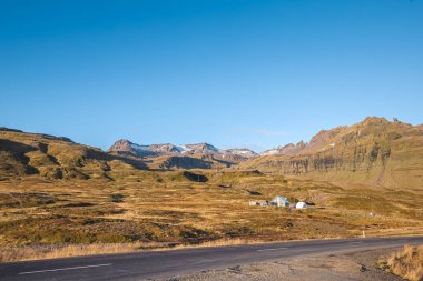 İzlanda 'daki Snaefellsnes yarımadasında açık mavi bir gökyüzünün altında uzanan altın tarlalar ve engebeli tepeler bu huzurlu sonbahar manzarasına hayat katıyor. Yaz mevsimi.