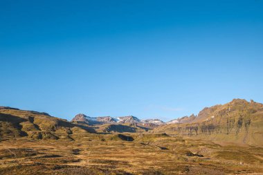 İzlanda 'daki Snaefellsnes yarımadasında açık mavi bir gökyüzünün altında uzanan altın tarlalar ve engebeli tepeler bu huzurlu sonbahar manzarasına hayat katıyor. Yaz mevsimi.