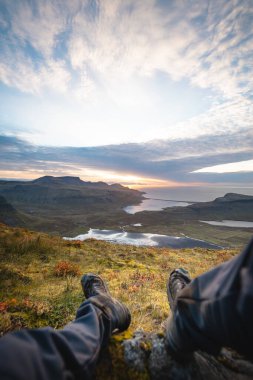 İzlanda 'daki Kirkjufell Dağı' nın tepesinde dinlenen bir yürüyüşçü fiyortların ve vadilerin üzerine dökülen güneş ışığına bakıyor. Mükemmel bir sakinlik, bağlantı ve saf özgürlük anı..