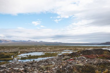 Kristal berrak suların dramatik gökyüzünün altında volkanik karayla buluştuğu İzlanda 'daki Thingvellir Ulusal Parkı' nın kıvrımlı nehirleri ve sulak alanları üzerindeki hava manzarası.