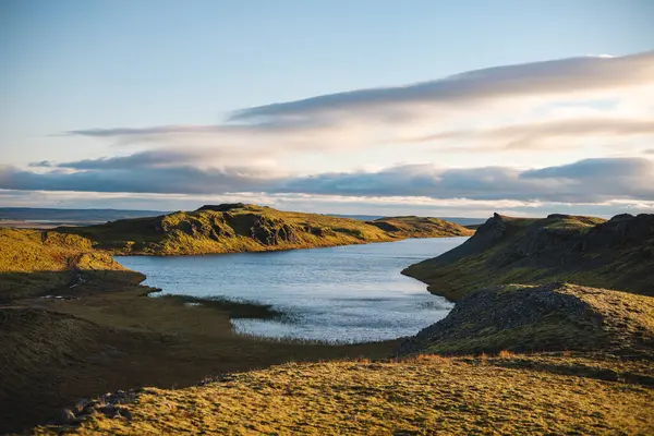 Hrunamannahreppur, İzlanda 'daki Hrunamannahreppur Dağı yakınlarındaki sakin göl ve yuvarlanan tepeler üzerinde altın saat. İzlanda kırsalında huzurlu bir günbatımı anı.