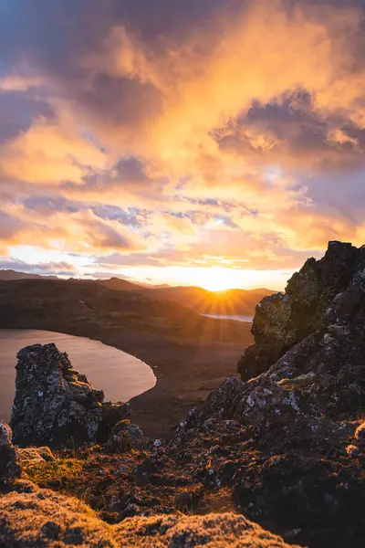 Altın güneş ışığı, İzlanda 'daki Snaefellsnes Yarımadası' ndaki Boynuz adlı dağın ufukta parlıyor. Gökyüzüne ve aşağıdaki volkanik topraklara çarpıcı bir ışık saçıyor..