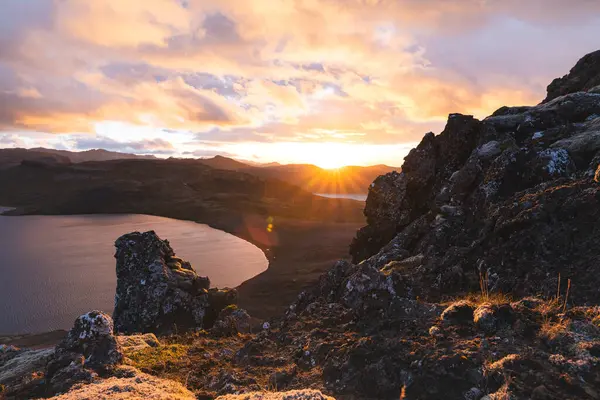 Altın güneş ışığı, İzlanda 'daki Snaefellsnes Yarımadası' ndaki Boynuz adlı dağın ufukta parlıyor. Gökyüzüne ve aşağıdaki volkanik topraklara çarpıcı bir ışık saçıyor..