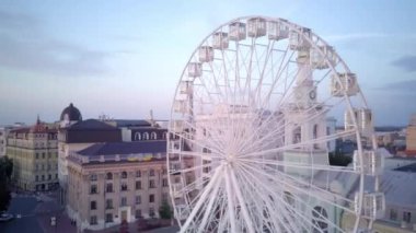 Kiev. İnsansız hava aracı videosu. Büyük beyaz dönme dolap ve turistler Kiev 'in Podolsk bölgesindeki Kontraktova Meydanı' nın ortasında yürüyorlar.