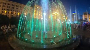 Independence Square. Kiev Kyiv. Ukraine. Aerial view of the fountains. Evening. People walk around the square. Building. On the road there are cars. Singing Fountains