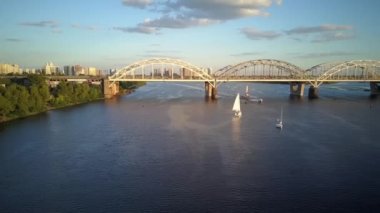 Üst hava manzaralı balıkçı teknesi okyanusu. Gün batımında Dnipro nehrinde balıkçıyla motorlu tekne gezintisi. Şehirdeki göllerin üzerindeki köprü manzarası. Su taşımacılığı, seyahat, yaz, dinlenme, rezervuarlar