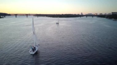 Üst hava manzaralı balıkçı teknesi okyanusu. Gün batımında Dnipro nehrinde balıkçıyla motorlu tekne gezintisi. Şehirdeki göllerin üzerindeki köprü manzarası. Su taşımacılığı, seyahat, yaz, dinlenme, rezervuarlar