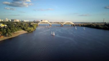 Üst hava manzaralı balıkçı teknesi okyanusu. Gün batımında Dnipro nehrinde balıkçıyla motorlu tekne gezintisi. Şehirdeki göllerin üzerindeki köprü manzarası. Su taşımacılığı, seyahat, yaz, dinlenme, rezervuarlar