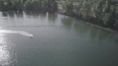 Cityscape with construction for weakboarding, Aerial shot of a cableway in a lake with a wakeboarder making turns and tricks. Sportsman grinding and rotating on a funbox. Girl wakeboarding in wake