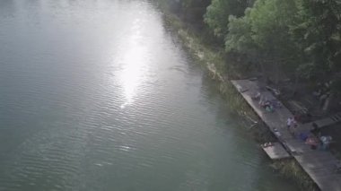 Cityscape with construction for weakboarding, Aerial shot of a cableway in a lake with a wakeboarder making turns and tricks. Sportsman grinding and rotating on a funbox. Girl wakeboarding in wake