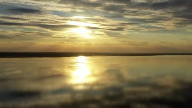 Big yellow sun rising over sea surface, Sunset on the big lake in summer, The drone flies over a big lake at sunset, a panoramic view with the stunning colours of the sunset in the background