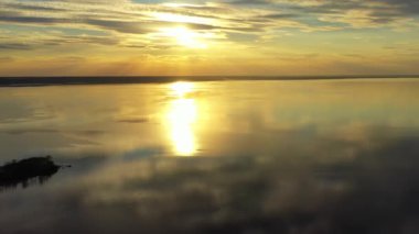 Big yellow sun rising over sea surface, Sunset on the big lake in summer, The drone flies over a big lake at sunset, a panoramic view with the stunning colours of the sunset in the background