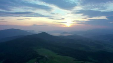 Gün batımında dağların manzarası. Karpat dağlarının panoramik manzarası yazın günbatımında güzel altın bir akşam ışığında parlıyordu..