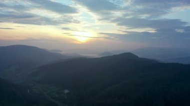 Gün batımında dağların manzarası. Karpat dağlarının panoramik manzarası yazın günbatımında güzel altın bir akşam ışığında parlıyordu..
