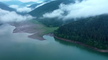 Turkuaz suyu ve yeşil ağaçları olan dağ gölü. Sudaki yansıma. Dağları, ormanı ve gölü olan güzel bir manzara. Hava görüntüsü. İnsansız hava aracı güzel bir dağ ormanı gölünün üzerinden geçti.